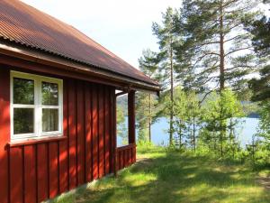 a red house with a window next to a body of water at Chalet Saglia - SOO020 by Interhome in Mjåvatn