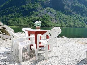 een tafel met drie witte stoelen en een meer bij Chalet Rødhette - FJS386 by Interhome in Gudvangen