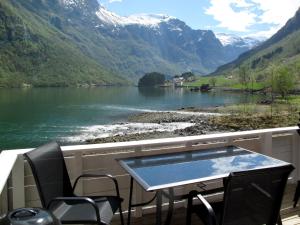 een tafel en stoelen op een balkon met uitzicht op een meer bij Chalet Rødhette - FJS386 by Interhome in Gudvangen