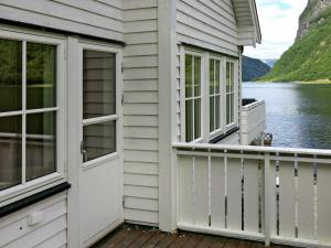 a house with a balcony with a door and a lake at Chalet Kvitveis - FJS392 by Interhome in Gudvangen