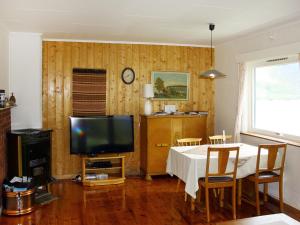 ein Wohnzimmer mit einem Tisch und einem TV in der Unterkunft Chalet Kårahuset - FJH408 by Interhome in Djønno