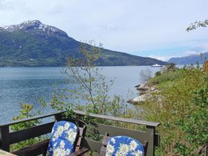 duas cadeiras azuis e brancas sentadas ao lado de um corpo de água em Chalet Slåttenes - FJH415 by Interhome em Naustflot