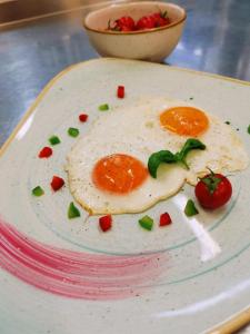 a plate with a fried egg and tomatoes on it at Villa Andor in Ankaran