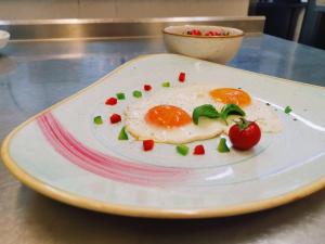 a plate with a fried egg and tomatoes on a table at Villa Andor in Ankaran