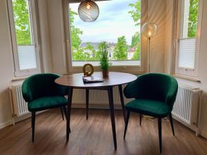 einen Tisch und zwei grüne Stühle in einem Zimmer mit Fenster in der Unterkunft Quartier 1903 in Oldenburg