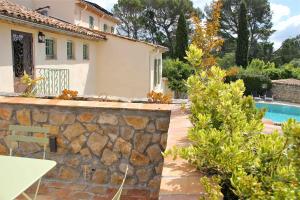 a house with a stone wall and a swimming pool at La Vieille Ferme de Grasse in Grasse