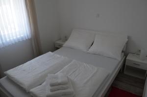 - un lit avec des draps blancs et des serviettes dans l'établissement Apartments Sušec, à Baška