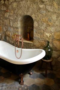 uma banheira num quarto com uma parede de pedra em La Vieille Ferme de Grasse em Grasse
