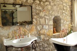 een stenen badkamer met een wastafel en een spiegel bij La Vieille Ferme de Grasse in Grasse