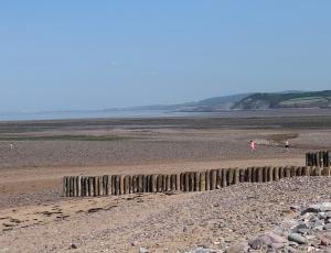 a rocky beach with people walking on the beach at Millstream Cottage B & B in Dunster