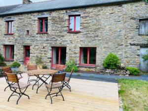 a patio with a table and chairs in front of a stone building at Ar Merglet - Grande longère authentique en Brocéliande in Maxent