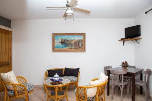 sala de estar con mesa, sillas y ventilador de techo en Appartements A Merendella en Serriera