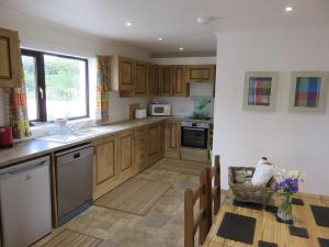 cocina con armarios de madera, fregadero y mesa en Skye Getaways Self Catering Accommodation, en Dunvegan