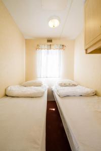 - 2 lits dans une petite chambre avec fenêtre dans l'établissement Rowyhills, à Rowy
