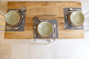 einen Tisch mit Tellern und Besteck auf einem Holztisch in der Unterkunft Dimora Don Vincenzo - Puglia Mia Apartments in Monopoli