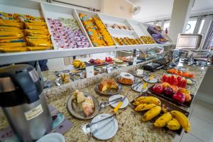 un buffet avec des bananes et d'autres aliments sur un comptoir dans l'établissement Hotel Tadini, à Santa Rita do Sapucaí
