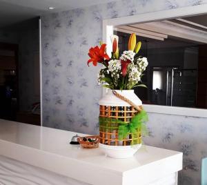 un jarrón de flores en una mesa frente a un espejo en Hotel Miramar 2** Superior, en A Lanzada