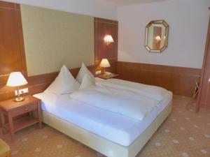 um quarto com uma grande cama branca e duas mesas em Hotel Garni Zerzer em Serfaus