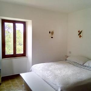 um quarto branco com uma cama e uma janela em Casa del Gigi BnB em Albareto