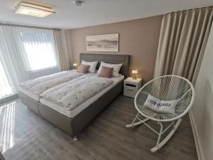ein Schlafzimmer mit einem großen Bett und einem Stuhl in der Unterkunft FeWo Hage in Langelsheim
