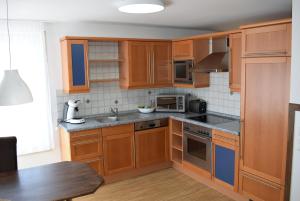 una cocina con armarios de madera y fregadero en Apartments mit Klimaanlage am Neckarufer, Schöne Aussicht en Bad Friedrichshall