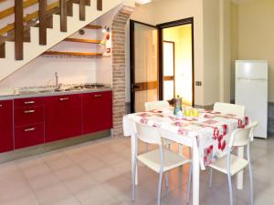 a kitchen with a table with white chairs and red cabinets at Holiday Home La Sirenetta by Interhome in Castiglione della Pescaia