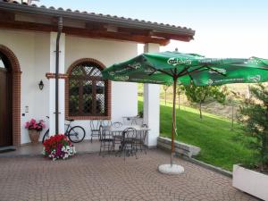 バローロにあるHoliday Home Collina San Ponzio by Interhomeの緑のパラソル、テーブル、椅子が備わるパティオ