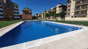 a large blue swimming pool with buildings in the background at Apartamento Naturaleza 2000 Jaca 1º in Jaca