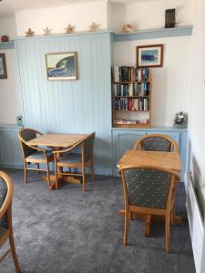 Habitación con mesa, sillas y estante para libros. en Trewinda Lodge, en Newquay