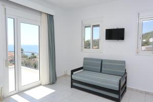a living room with a couch and a tv and windows at Maison Ciel in Agia Paraskevi