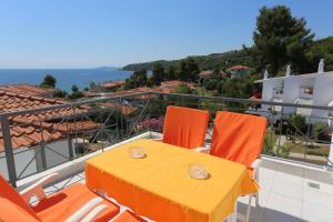 a yellow table and orange chairs on a balcony at Maison Ciel in Agia Paraskevi
