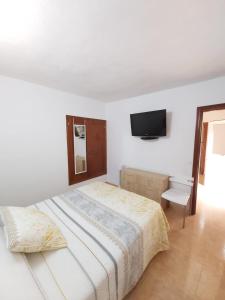 ein Schlafzimmer mit einem Bett und einem Fernseher an der Wand in der Unterkunft La casita de Candida in Tigaday