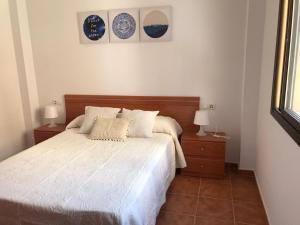 een slaapkamer met een wit bed met 2 nachtkastjes en 2 lampen bij Apartamento en Fuengirola junto al paseo marítimo in Fuengirola