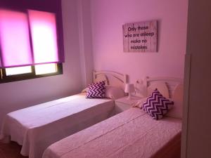 twee bedden in een kamer met roze muren en ramen bij Apartamento en Fuengirola junto al paseo marítimo in Fuengirola