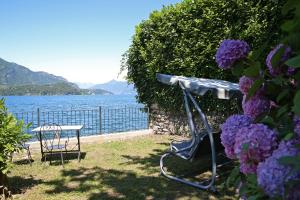 una mesa y sillas junto al agua con flores en Hotel Helvetia en Lezzeno