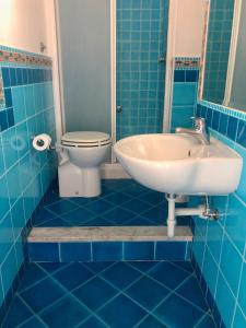 bagno piastrellato blu con lavandino e servizi igienici di Residenza Celeste al 28 a Ischia