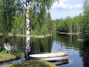 a boat and a chair sitting on a lake at Chalet Ramsjö by Interhome in Ramsjö