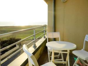 Un balcón con sillas y mesas y vista al mar. en Apartment Pamplemousse Face Mer by Interhome, en Les Bains