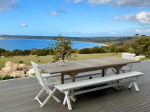 a wooden table and bench on a deck with a view of the water at The Cape in Emu Bay