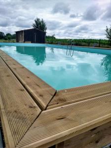 a large swimming pool with a wooden deck at La maison de pescate in Souprosse