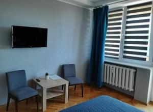 sala de estar con 2 sillas, mesa y TV en Doba Rent POKOJE CENTRUM PAŁACOWA, en Białystok