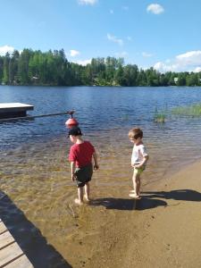 two children standing on the shore of a lake at Rämäkkä Holidays in Rautalampi