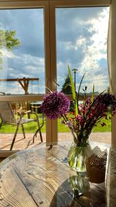 a glass table with a vase with purple flowers on it at Agroturystyka Widokówka Nielisz in Nielisz