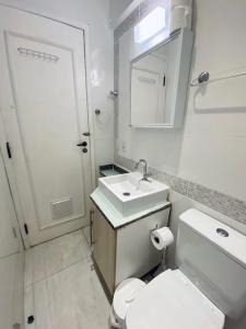 Baño blanco con lavabo y aseo en Aparts Ilha Centro-casa 2 qtos e casa 1 qto mezanino, en Florianópolis