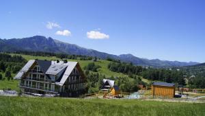 a house in a field with mountains in the background at Apartamenty Bachledzki Wierch in Zakopane