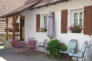 eine Terrasse mit Stühlen, einem Tisch und einem Sonnenschirm in der Unterkunft Gîte de charme au coeur du vignoble alsacien in Bernardvillé