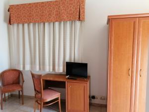 Habitación con escritorio, TV y silla. en Hotel Giardino en Modugno