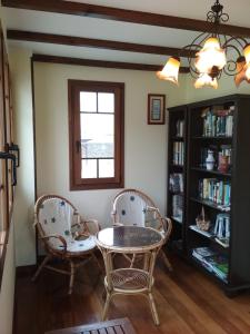 Habitación con 2 sillas, mesa y estante para libros en Casa Fonso en Villapedre