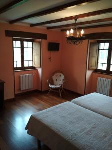 a bedroom with two beds and a chair and windows at Casa Fonso in Villapedre