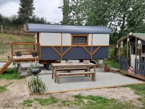 een blauwe en witte trailer met een tafel en een bank bij LA ROULOTTE DE GERMAINE in Condé-sur-Vire